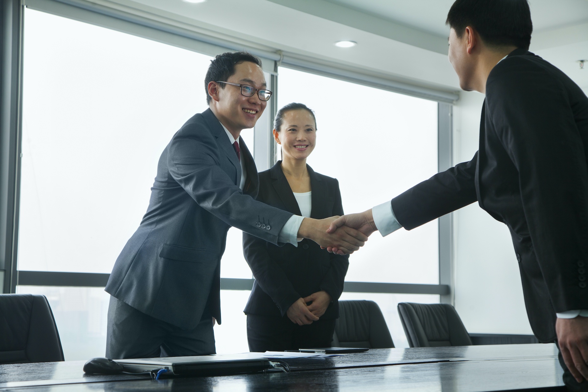 Zwei chinesische Businessmänner schütteln sich bei einem Meeting die Hand