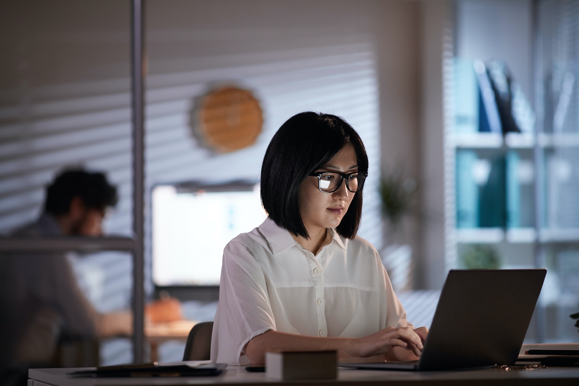 Junge asiatische Frau arbeitet an einem Laptop im dunkeln