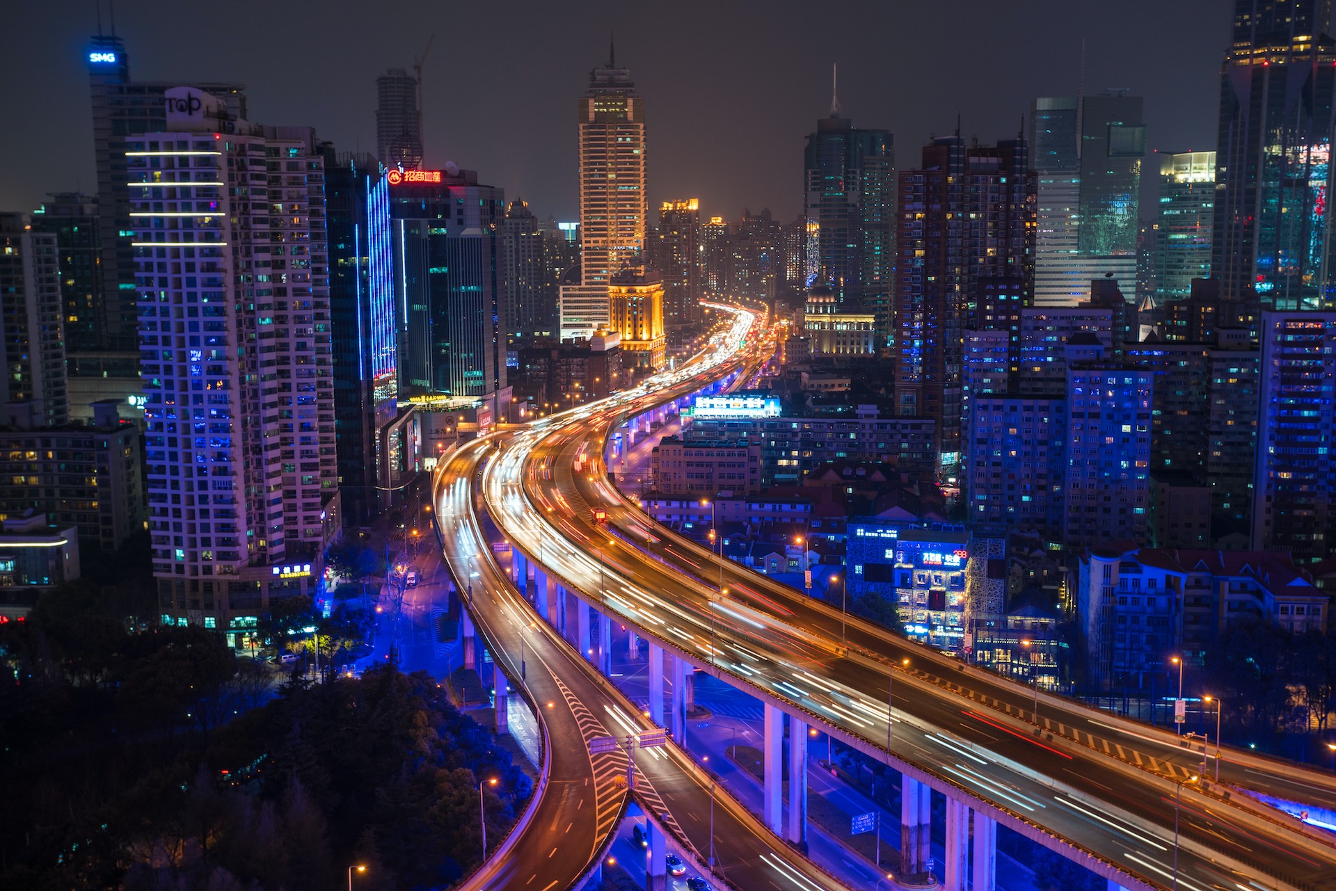 Shanghai Skyline bei Nacht mit Autos auf der Straße und leuchtenden Gebäuden