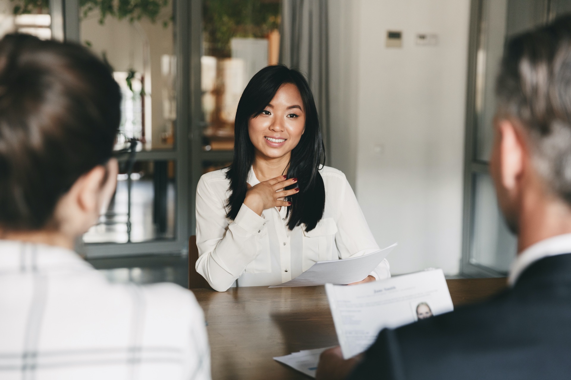 Junge chinesische Business Frau, die lächelt und ein Dokument Ihrem Team reicht